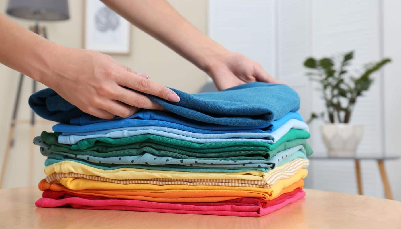 woman placing folded clothes into pile